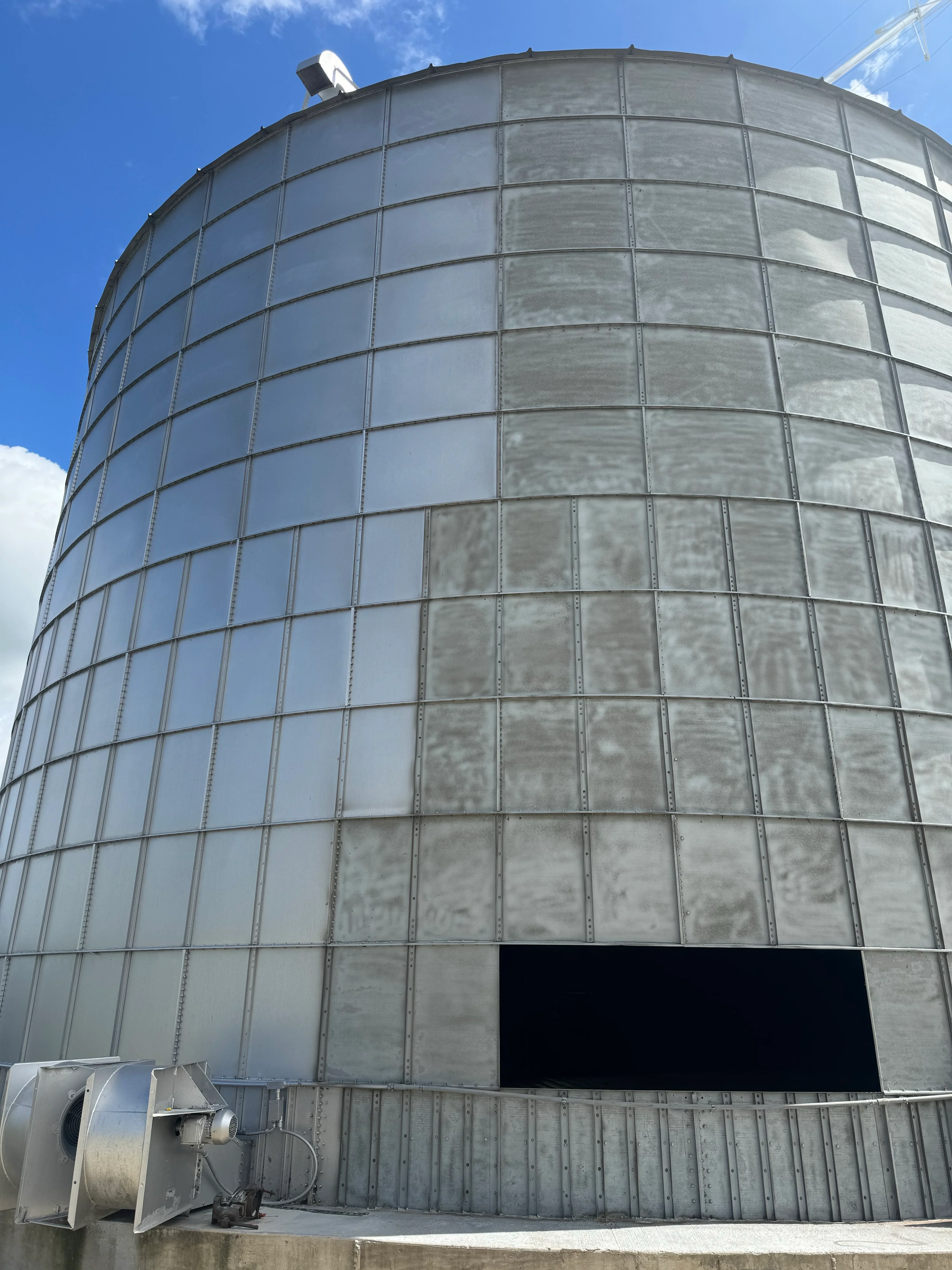 Large cylindrical metal storage tank with sandblasted and restored galvanized steel panels and framework