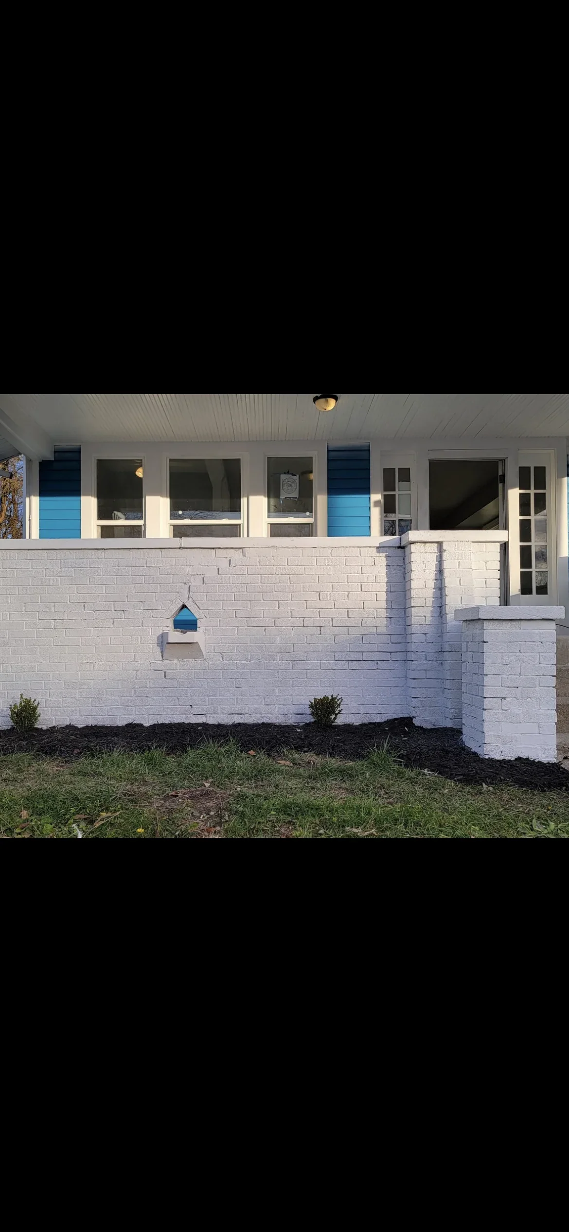 White brick foundation after sandblasting, with clean masonry surface and black mulch landscaping