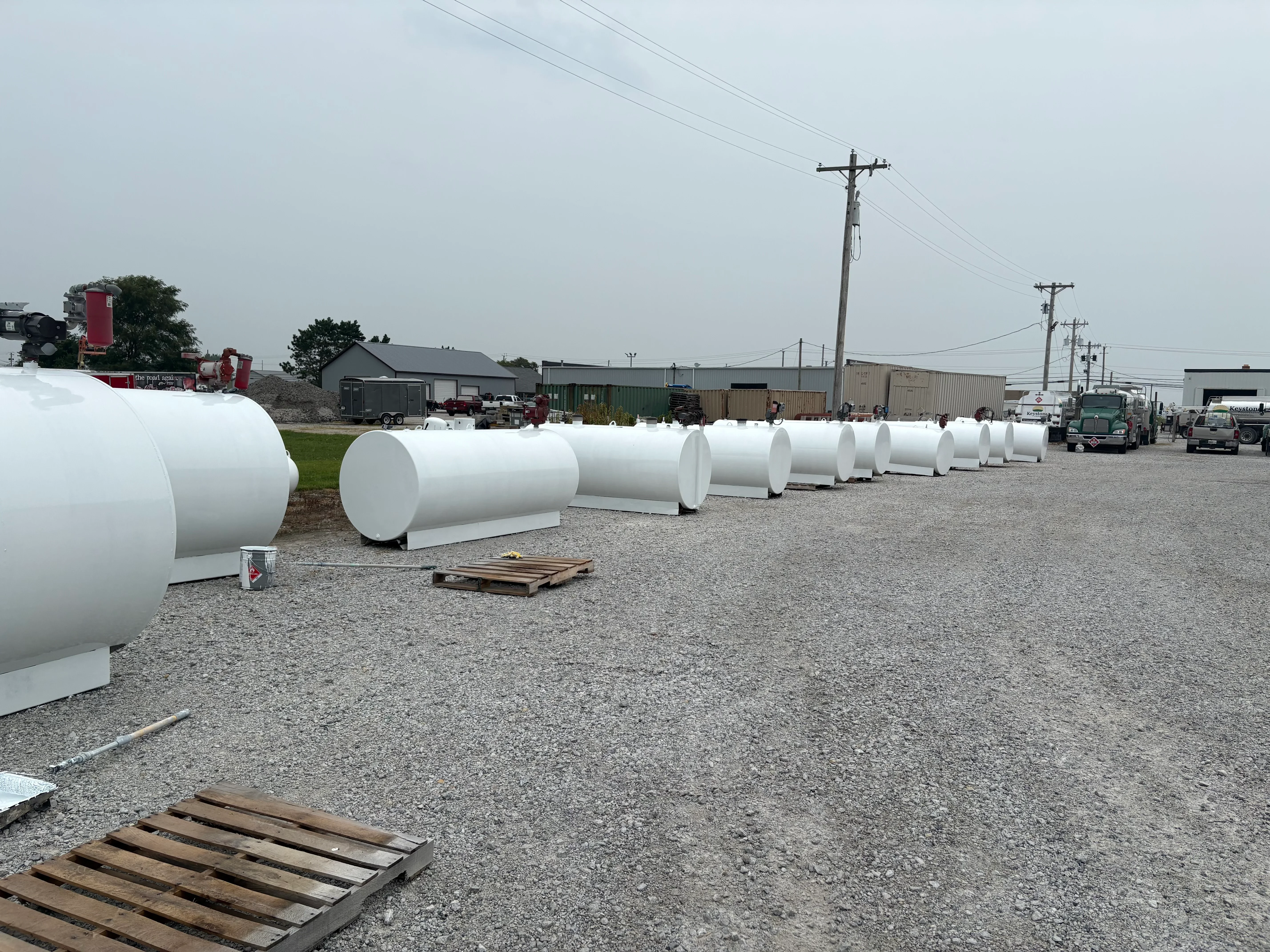 Row of white cylindrical steel tanks prepared with sandblasting and primer coating