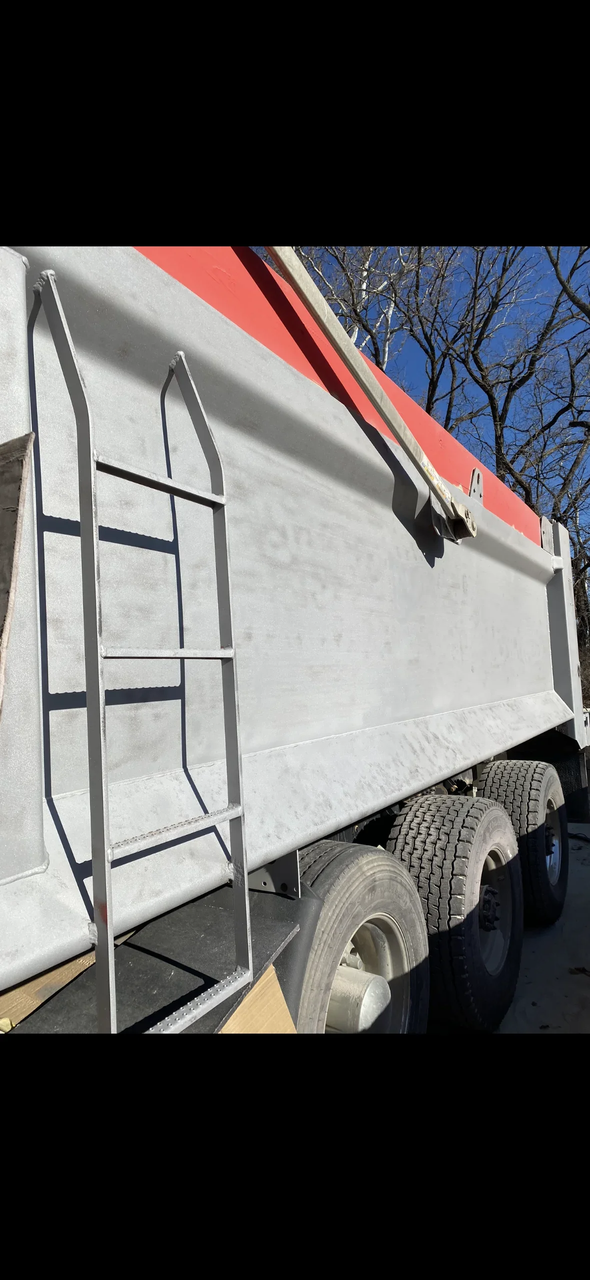 Sandblasted commercial trailer with white aluminum body and metal access ladder, ready for coating