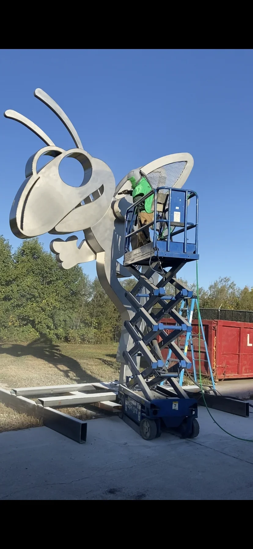 Sandblasting large metal insect sculpture with cream finish using mobile lift and equipment