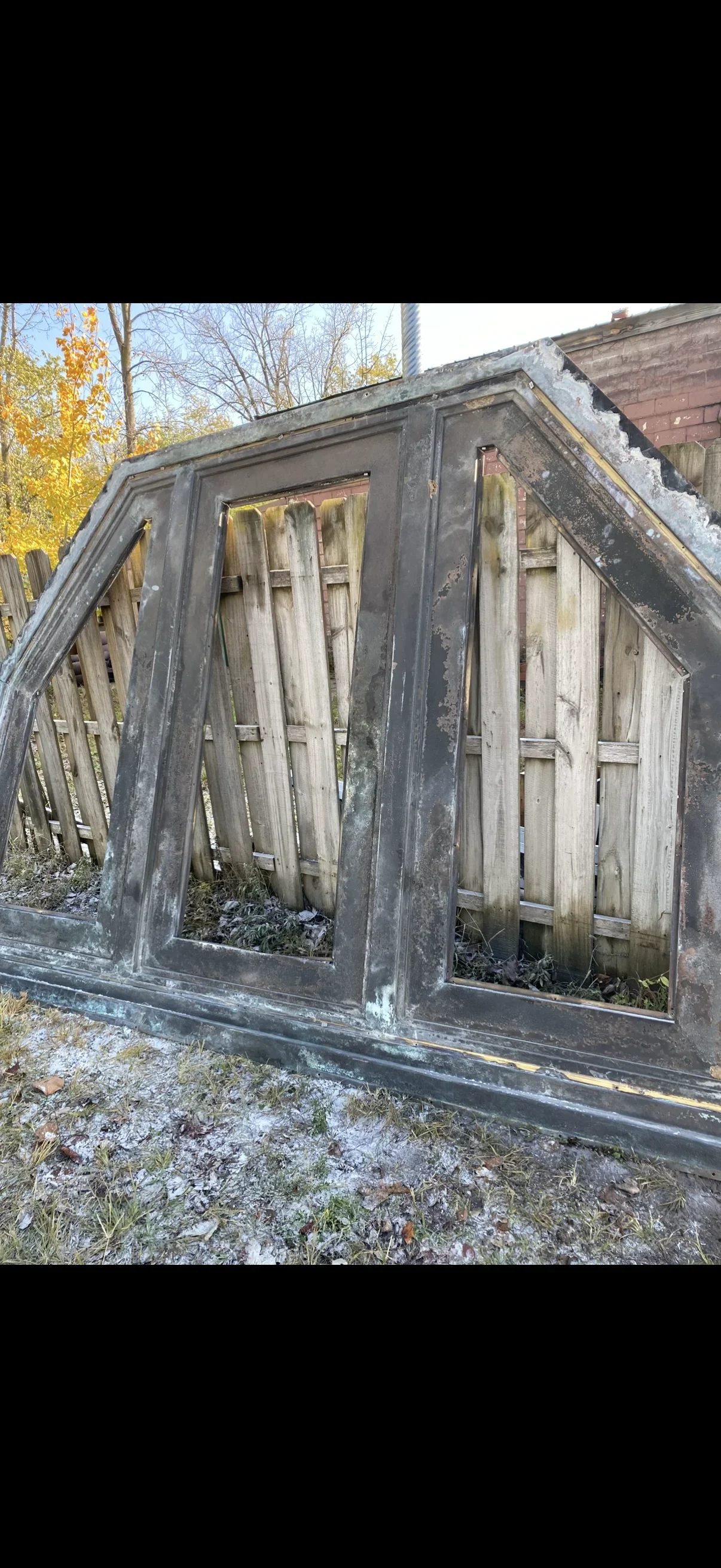 Weathered metal structure with corroded steel frame and deteriorated wooden louvers before restoration