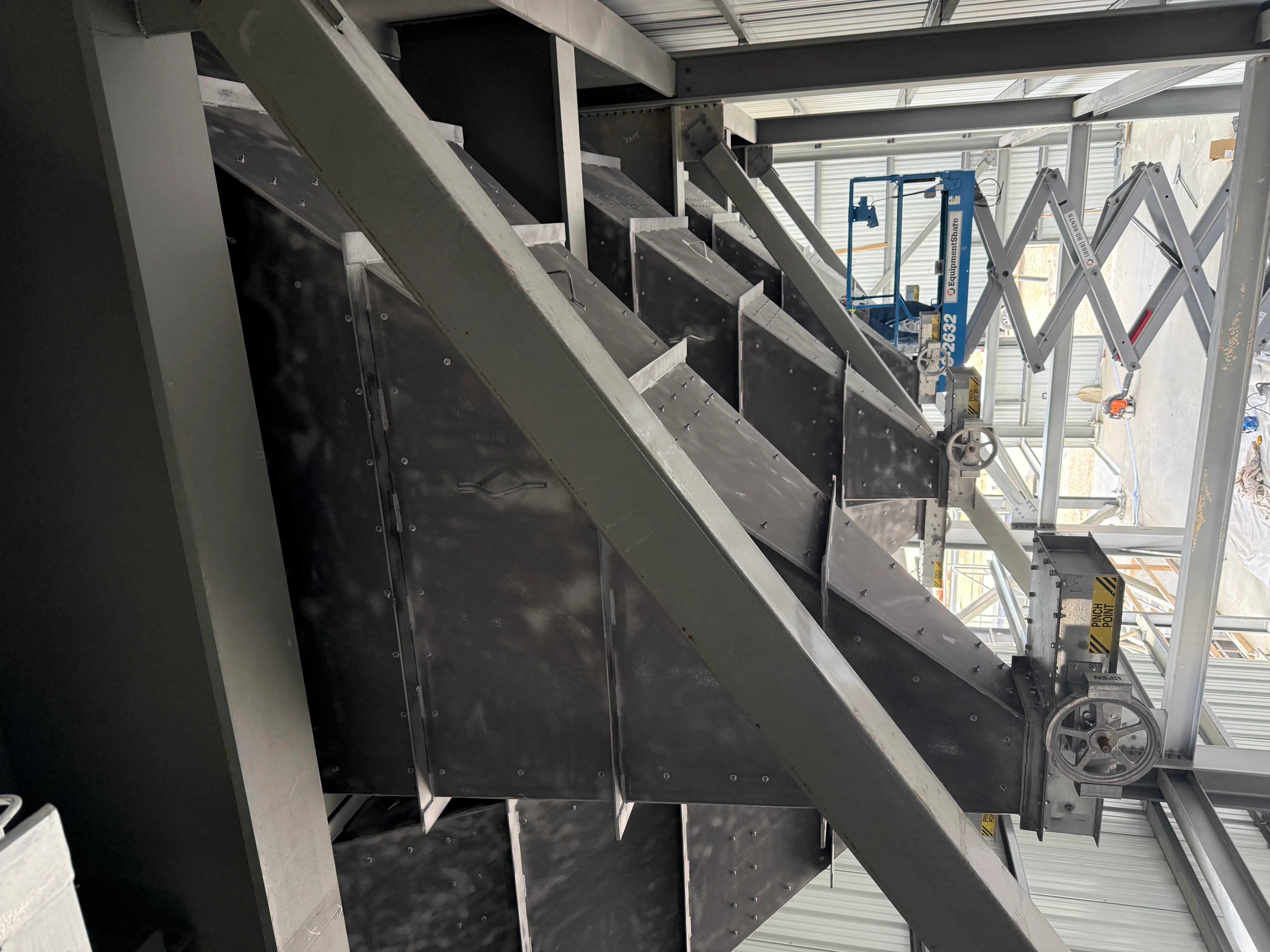 Sandblasted steel panels and industrial equipment framework with protective coverings and scaffolding